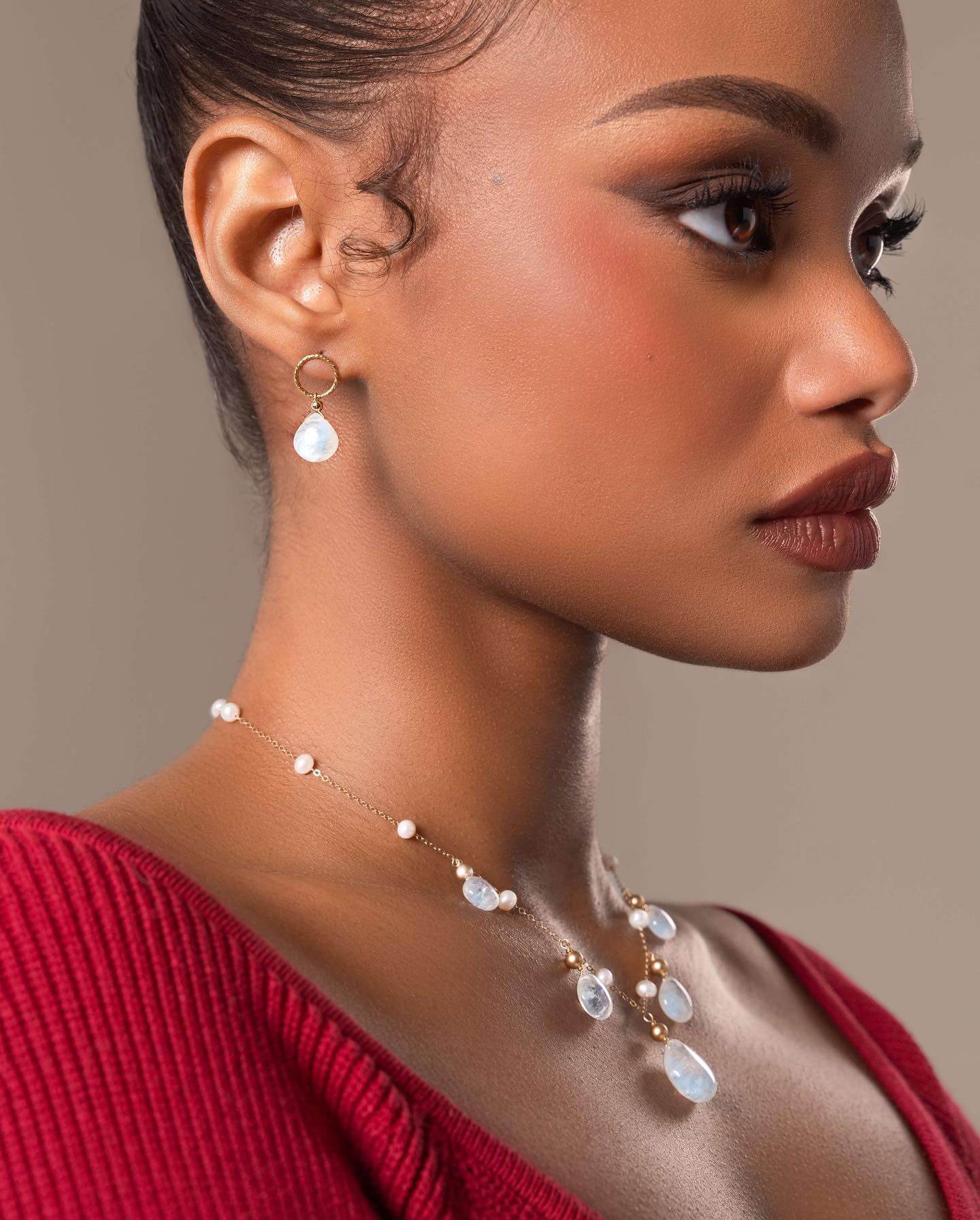 Woman wearing a necklace and earrings against a neutral background
