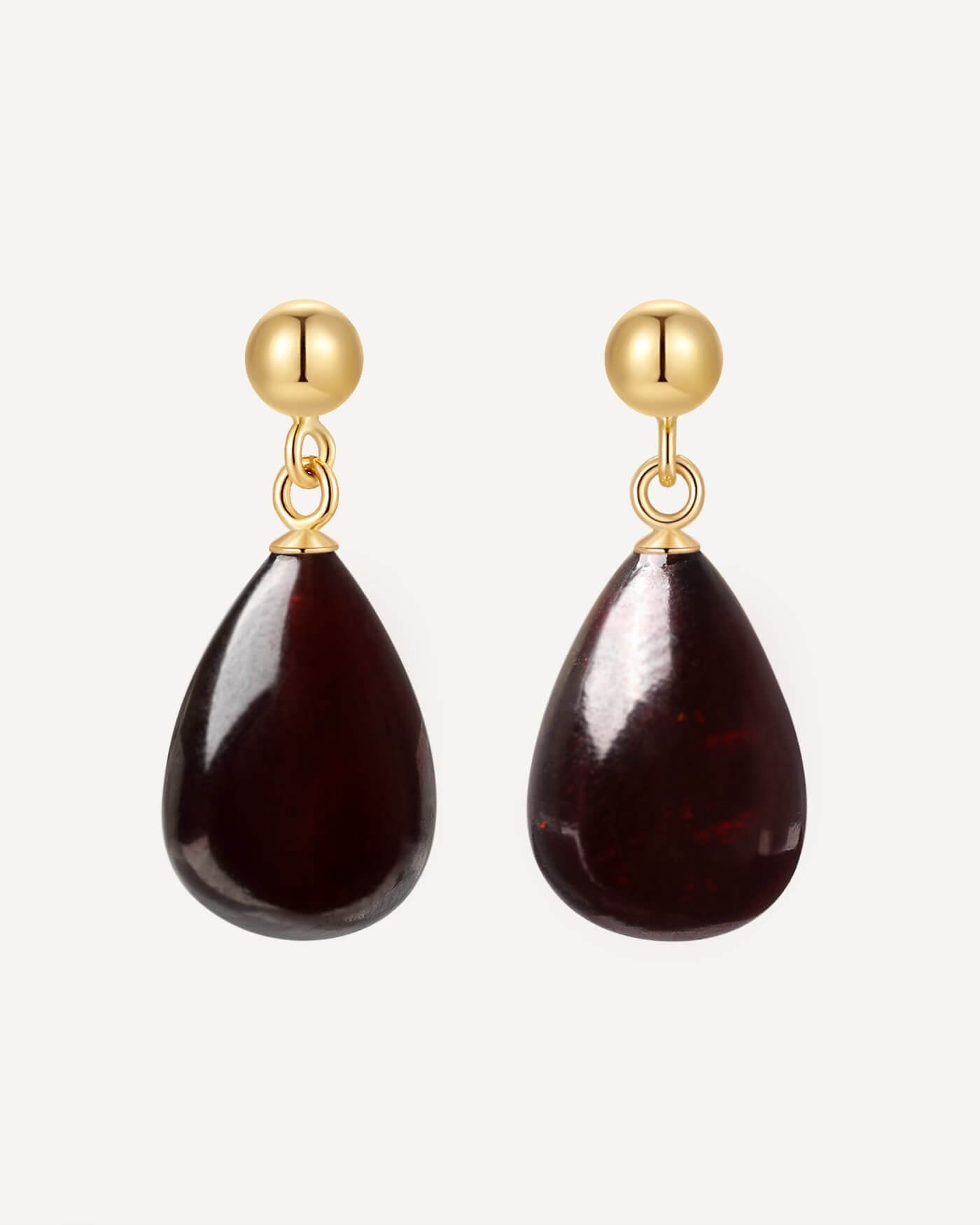 Gold earrings with teardrop-shaped dark red stones on a white background