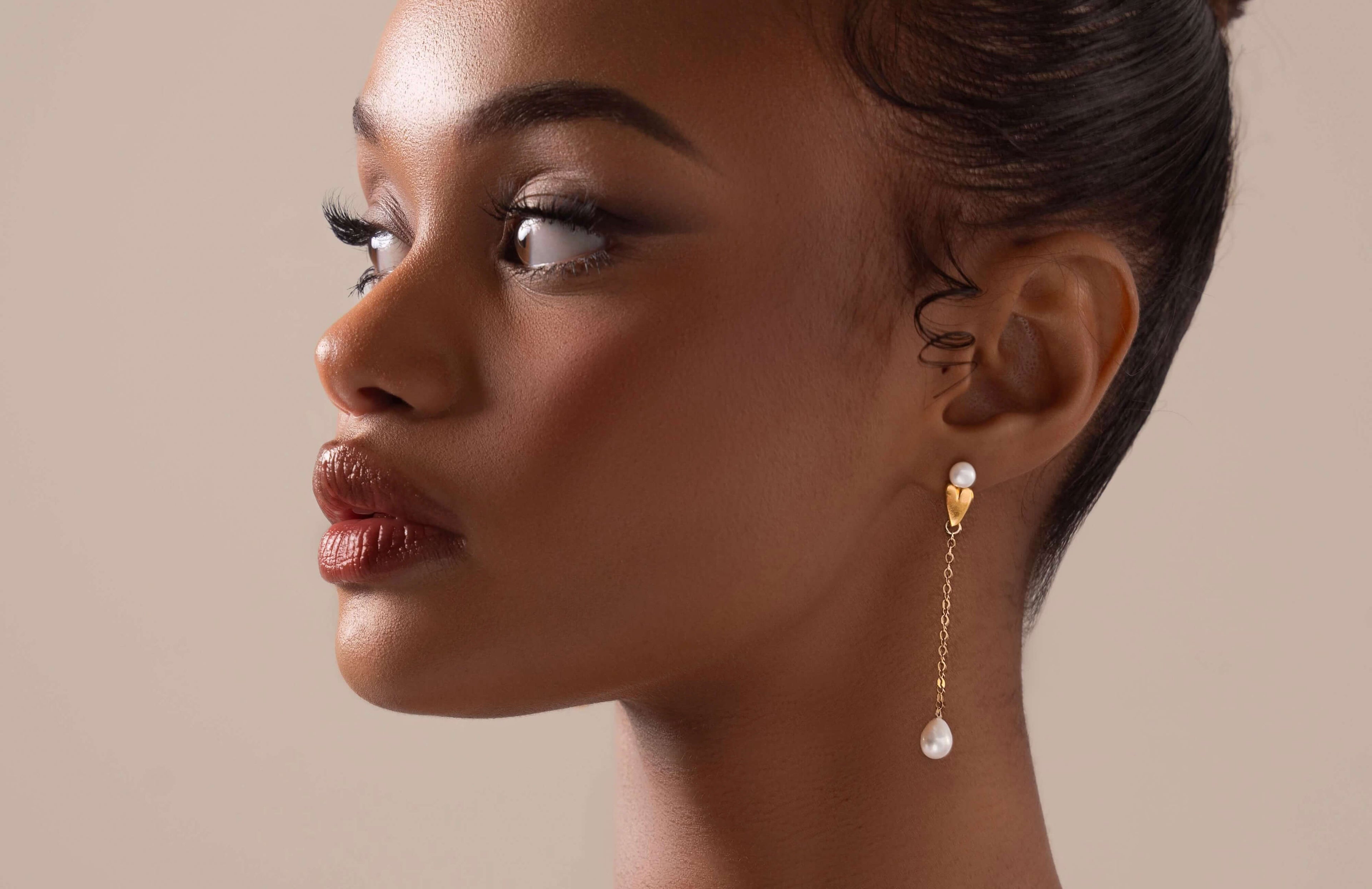 Close-up of a woman wearing pearl earrings with a neutral background