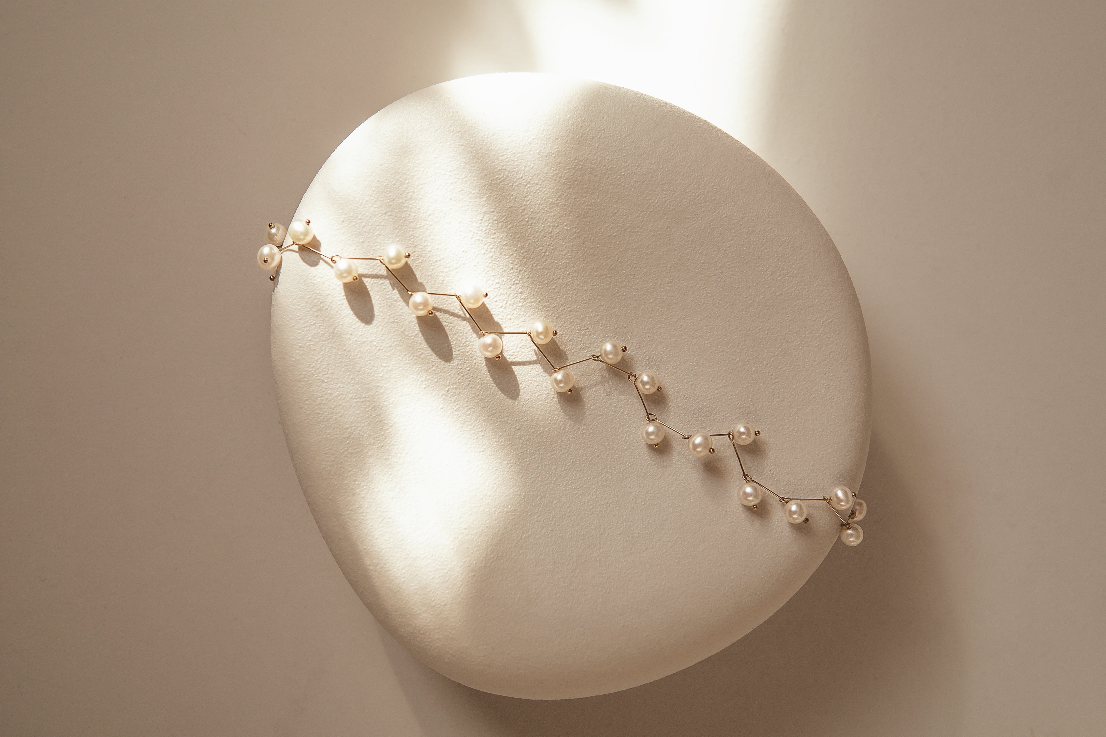 Delicate gold necklace on a round stone surface with soft lighting