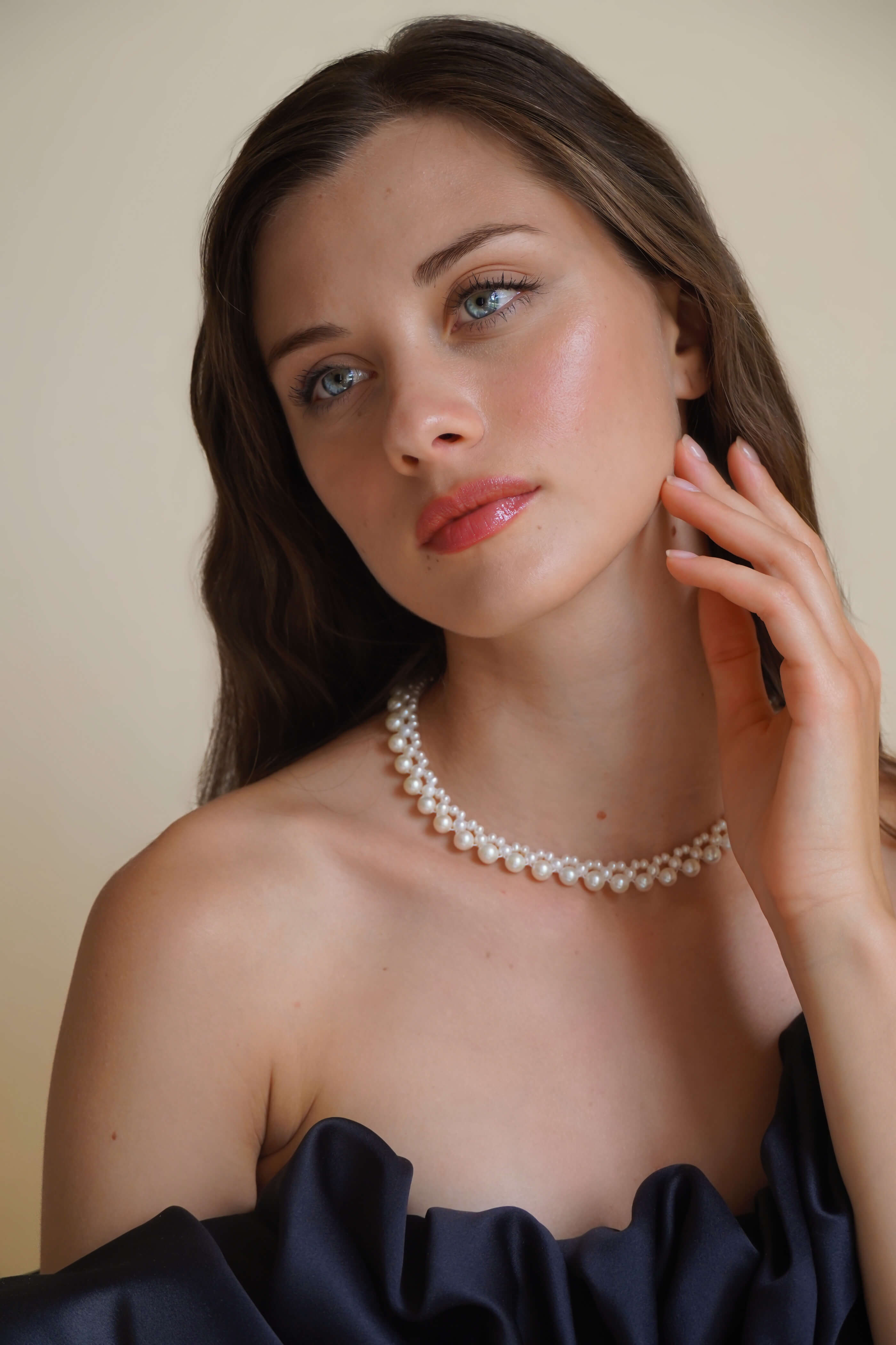 Pearl necklace worn by a woman with a neutral background