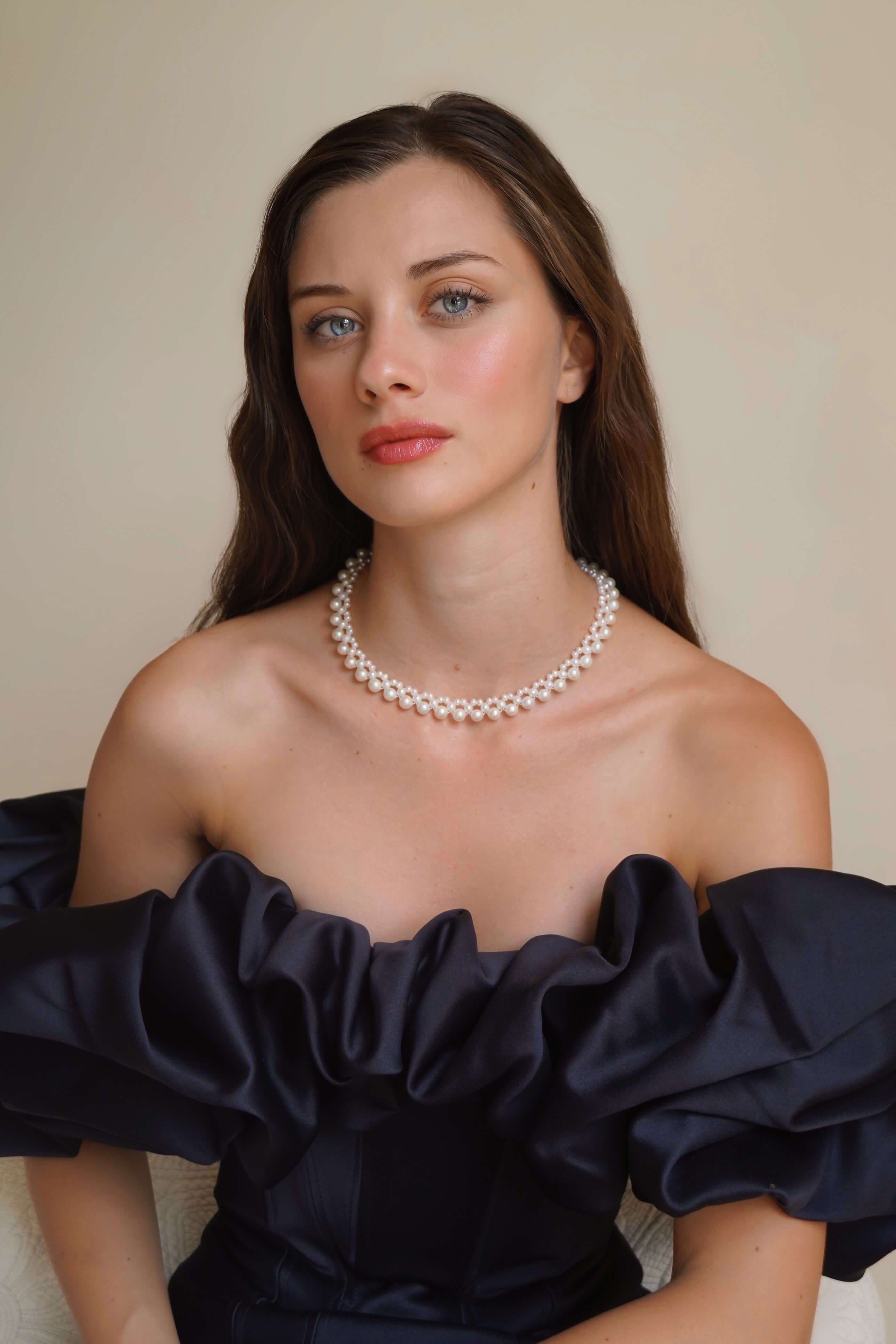 Woman wearing a pearl necklace against a plain background
