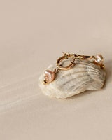 Shell-shaped keychain with a pink heart on a beige background