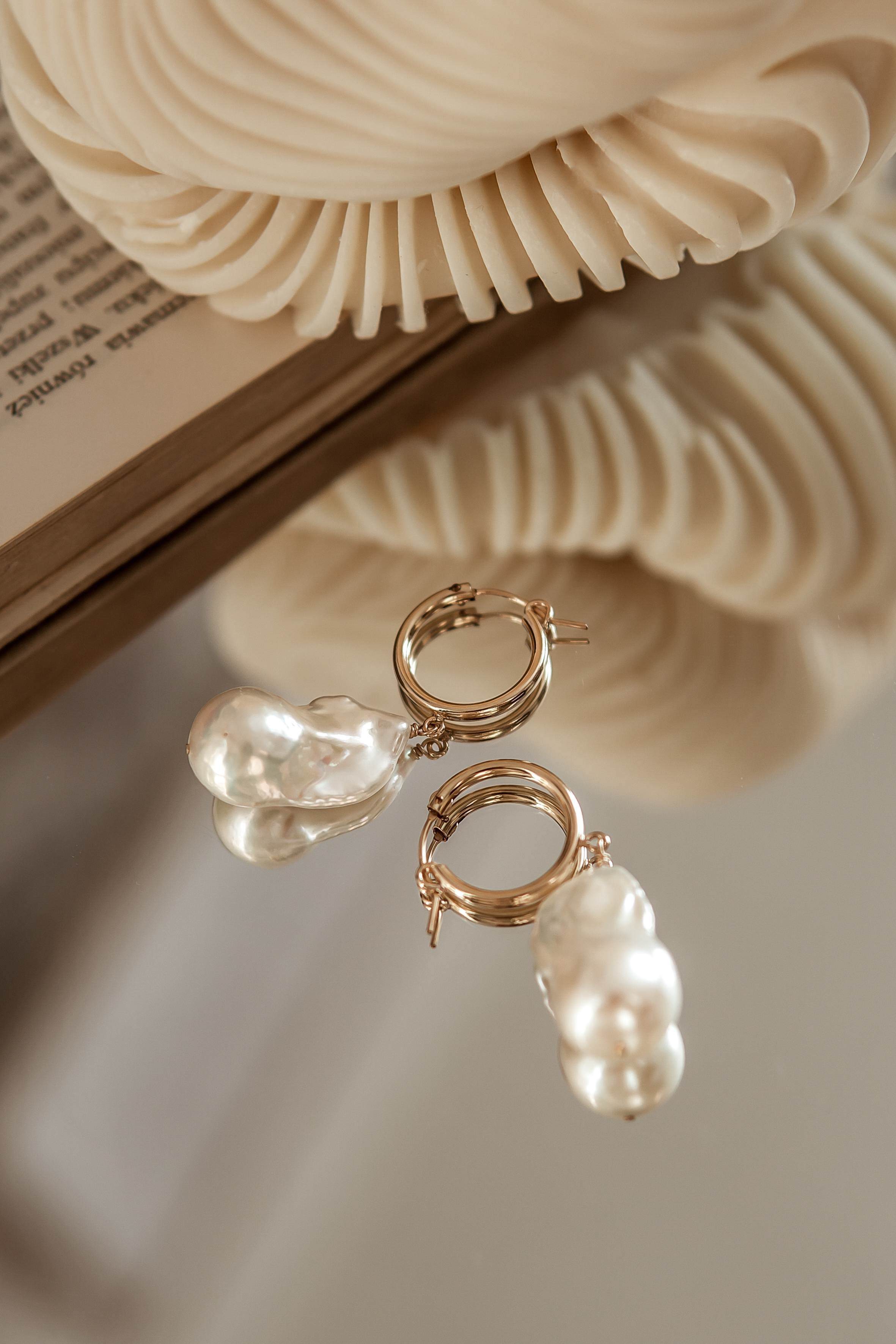 Pearl earrings on a textured surface with a blurred background
