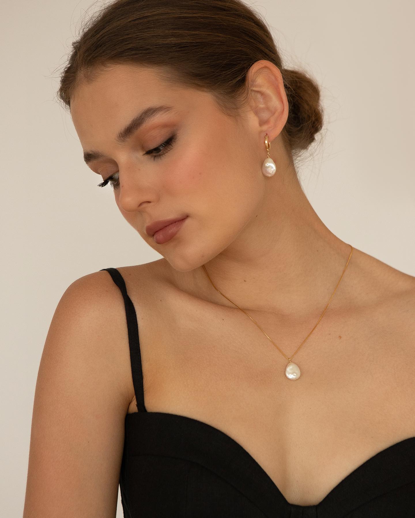 Woman wearing a necklace and earring set against a neutral background