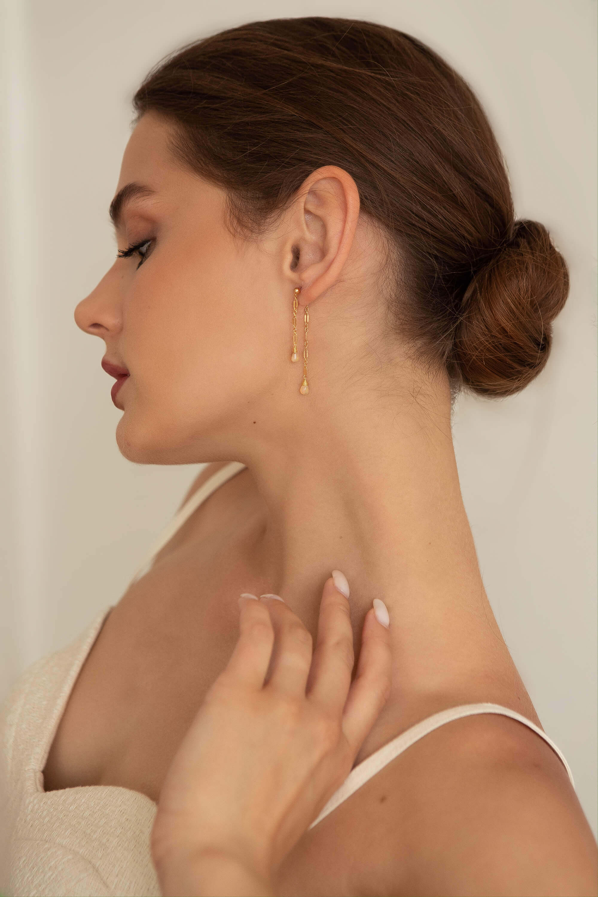 Woman wearing gold earrings with a neutral background