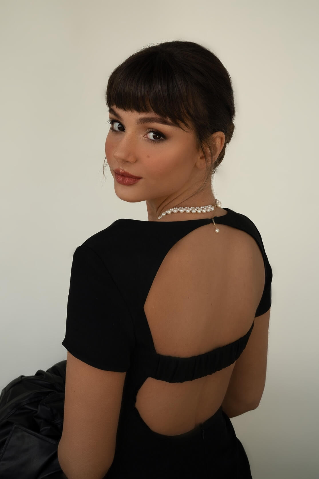 Woman wearing a pearl necklace against a plain background